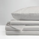The Morgan and Reid Hotel 1500 Thread Count Cotton Rich Sheet Set, with pillowcases and one pillow on top, is neatly stacked and displayed against a plain light gray background.