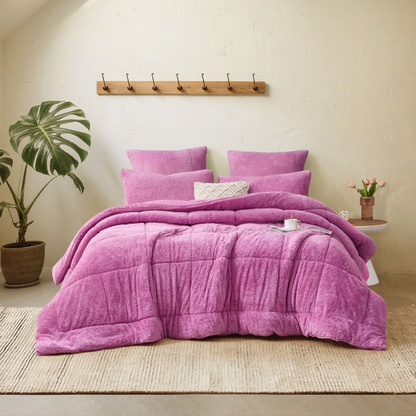 A vibrant crocus pink Snuggle Fleece Comforter set with layered pillows, adding warmth and colour to a modern bedroom.