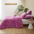 A vibrant crocus pink Snuggle Fleece Comforter set with layered pillows, adding warmth and colour to a modern bedroom.