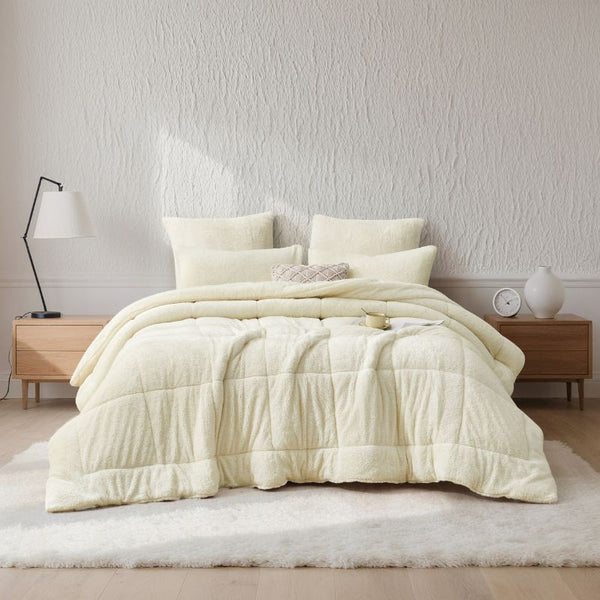 An ivory Snuggle Fleece Comforter set styled in a bright bedroom with a soft rug and timber accents for a calm, welcoming feel.