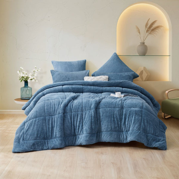 Blue comforter set on a bed in a bedroom with decorative elements.