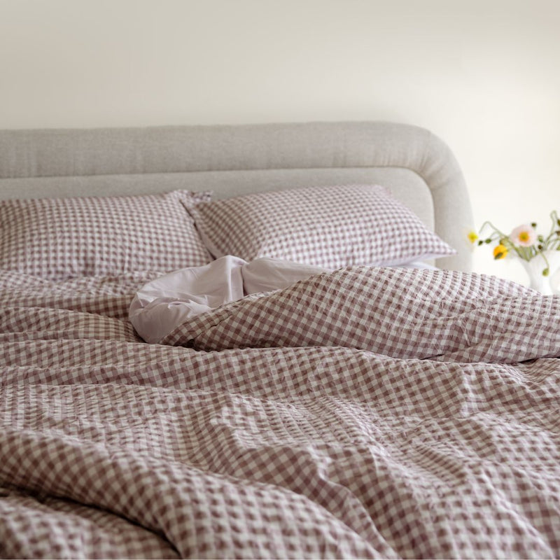 Bed with checkered bedding and pillows in a softly lit room.