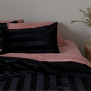 Bed with pink and black bedding against a neutral wall.