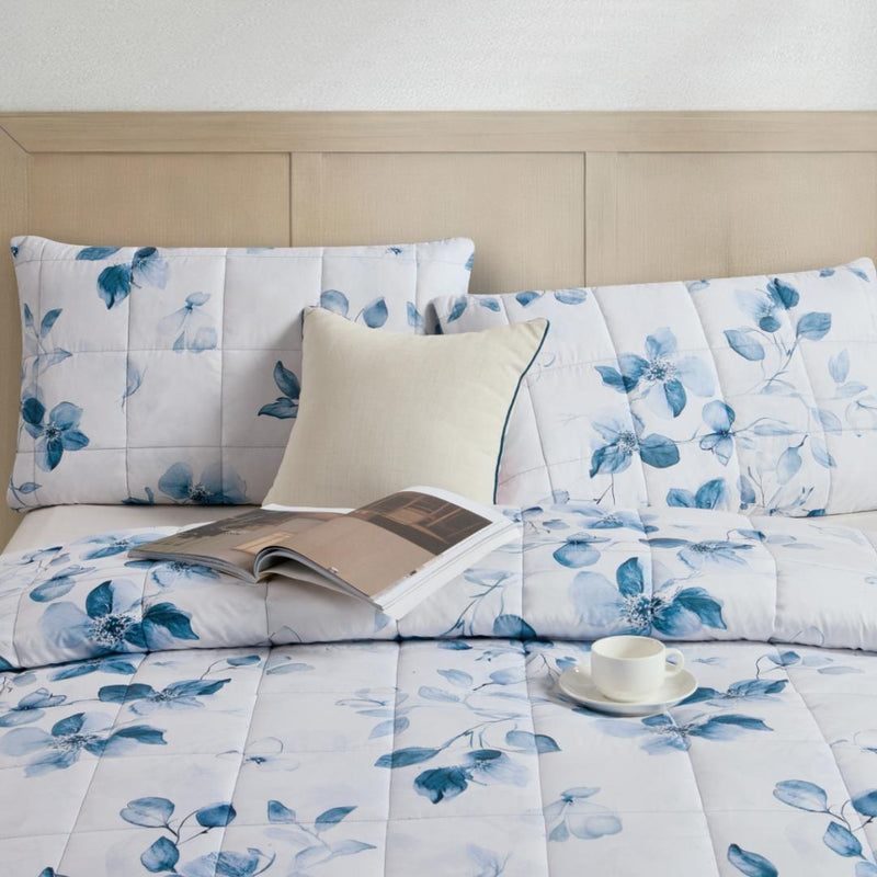 Lightweight quilted coverlet with matching pillowcases in soft blue floral design.