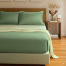 Bed with green bedding and a wooden headboard in a room with a side table and decor.