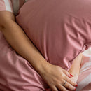 Close-up of a person's hands holding a pink pillow with a soft focus on the background.
