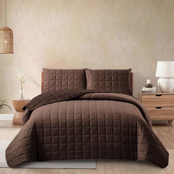Brown quilted bedding set on a bed in a bedroom setting.