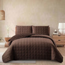 Brown quilted bedding set on a bed in a bedroom setting.
