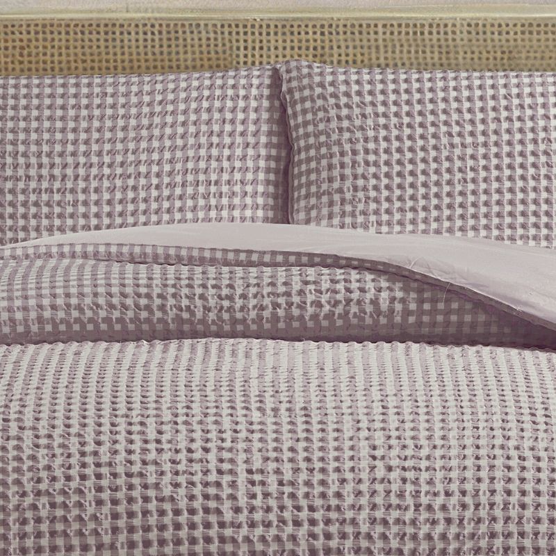 Textured bedspread with checkered pattern on a bed with wicker headboard