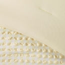 A modern bedroom features the Morgan and Reid Lemon Butter Gingham Comforter Set on a neatly made bed with matching pillowcases, rattan bedhead, neutral walls, woven pendant light, and a wooden side table with decorative accents.