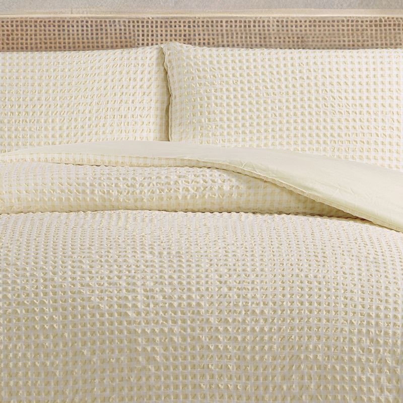 Close-up of textured beige bedding on a bed with a wicker headboard.