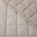 Close-up of a quilted fabric with diamond pattern in beige color.