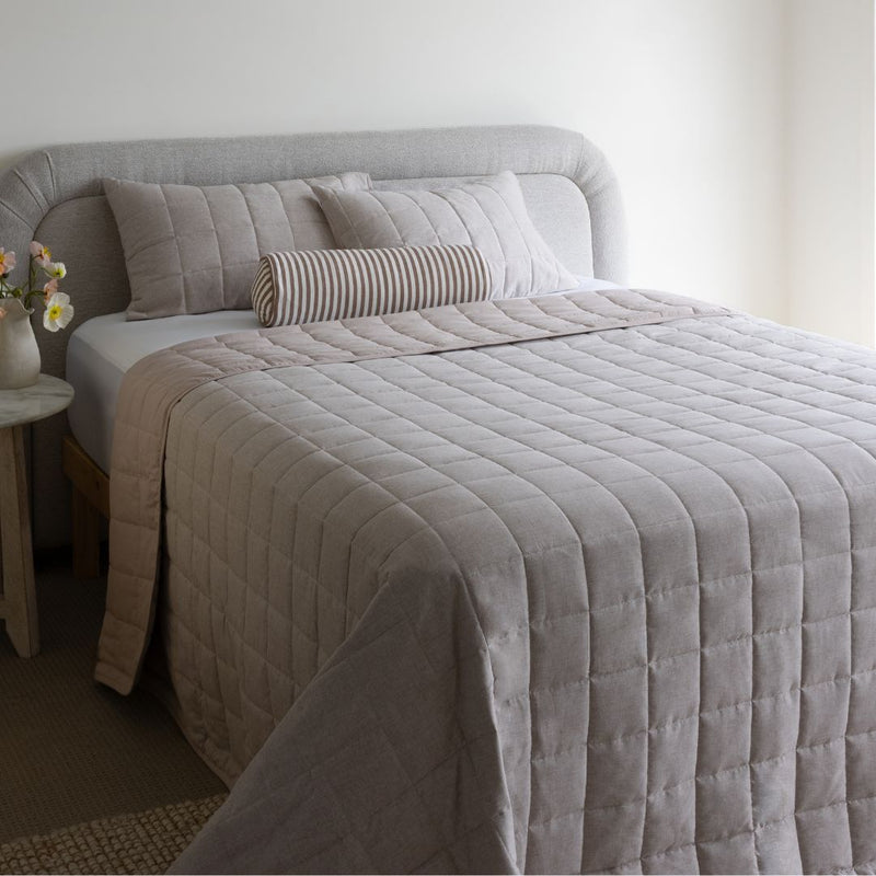 Bed with gray quilt and pillows in a bedroom setting