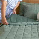 lady hands folding green quilt