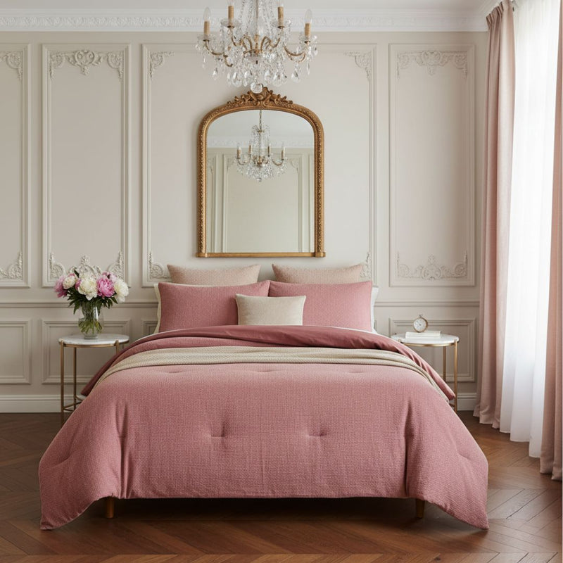 Pink bedspread on a bed in a stylish bedroom with a mirror and chandelier.
