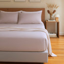 Neatly made bed with light bedding in a bedroom setting.