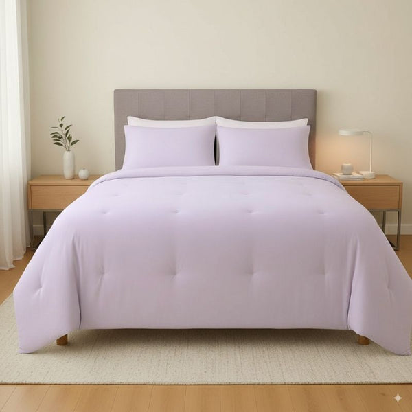 Bed with lavender bedding and pillows in a bedroom setting