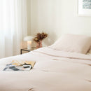 Neatly made bed with light bedding in a bright bedroom.