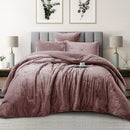 Pink textured comforter set on a bed in a bedroom with lamps and framed pictures.