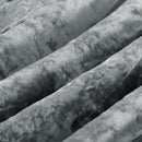 A neatly made bed features the Morgan and Reid Silver Velvet Crushed Snuggle Fleece Comforter Set with matching pillows, flanked by dark nightstands and modern lamps. A white cup and saucer sit on the comforter. The wall is dark gray.