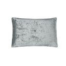 A neatly made bed features the Morgan and Reid Silver Velvet Crushed Snuggle Fleece Comforter Set with matching pillows, flanked by dark nightstands and modern lamps. A white cup and saucer sit on the comforter. The wall is dark gray.