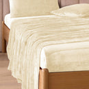 A modern bedroom with a beige upholstered bed and cream bedding exudes winter comfort, enhanced by the Morgan and Reid Winter Microplush Sheet Sets ultra-soft fabric, neutral decor, dried flowers, and light wood floors.