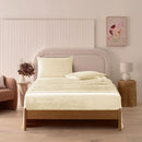 A modern bedroom with a beige upholstered bed and cream bedding exudes winter comfort, enhanced by the Morgan and Reid Winter Microplush Sheet Sets ultra-soft fabric, neutral decor, dried flowers, and light wood floors.