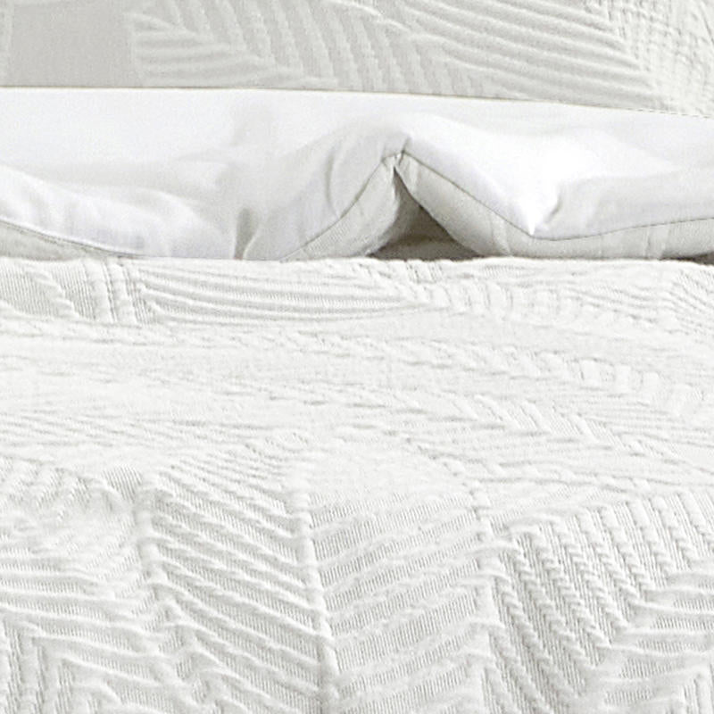 Soft textured white quilt cover creating a relaxed coastal-inspired bedroom look.