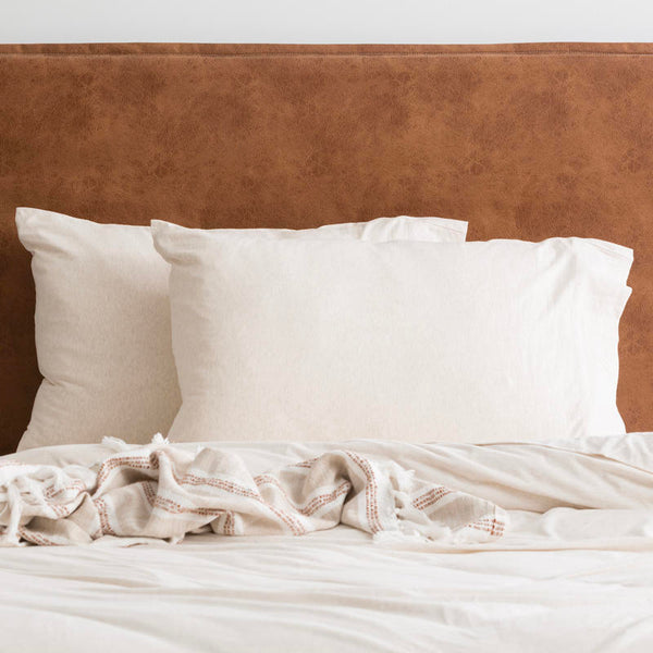 Oatmeal organic cotton jersey pillowcase set styled on a soft, neutral bed.