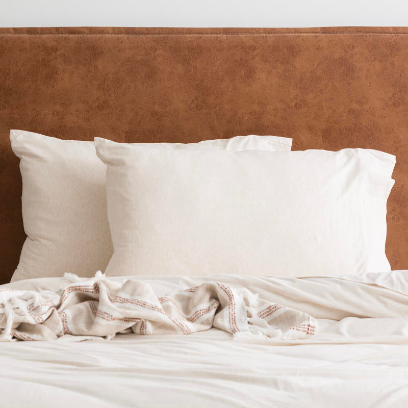 Oatmeal organic cotton jersey pillowcase set styled on a soft, neutral bed.
