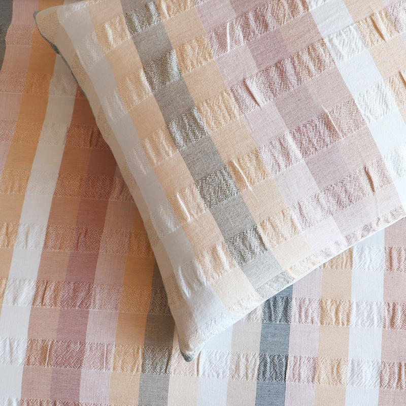Styled bed featuring Renee Taylor Layla European Pillowcases in blush, peach, and grey tones.