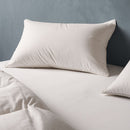 A neatly made bed features the Sienna Living 80% Duck Down 20% Feather Pillow, fluffed and placed at the head. The crisp white bedding and textured gray wall complete the clean, minimal look.