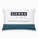 A neatly made bed features the Sienna Living 80% Duck Down 20% Feather Pillow, fluffed and placed at the head. The crisp white bedding and textured gray wall complete the clean, minimal look.