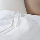 A neatly made bed features the Sienna Living All Seasons Hungarian Goose Down Quilt and white pillows against a dark blue paneled wall. A wooden bench at the foot of the bed adds all-season versatility to this clean, modern look.