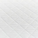 Close-up of the Sienna Living Premium Cotton Mattress Protector featuring a quilted cotton japara cover and diamond stitch pattern, fitted securely over a mattress with a grey upholstered base. Knit stretch skirt ensures a snug fit around corners.