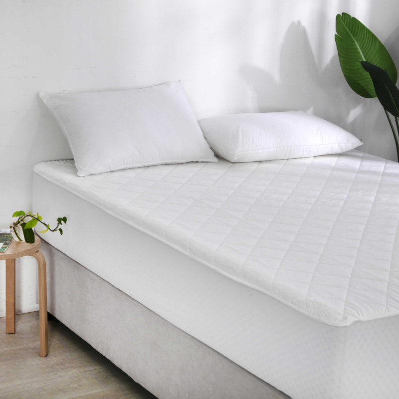 alt="A premium natural cotton mattress protector used in a luxurious bedroom"