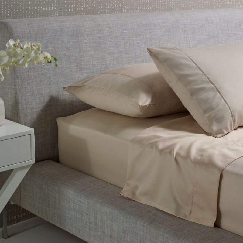 alt="A brown and plain cotton sheet set in a luxurious bedroom"