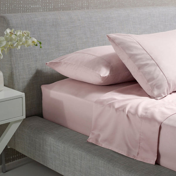 alt="A pink and plain cotton sheet set in a luxurious bedroom"