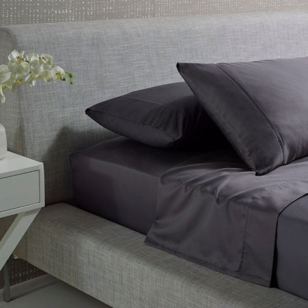 alt="A charcoal and plain cotton sheet set in a luxurious bedroom"