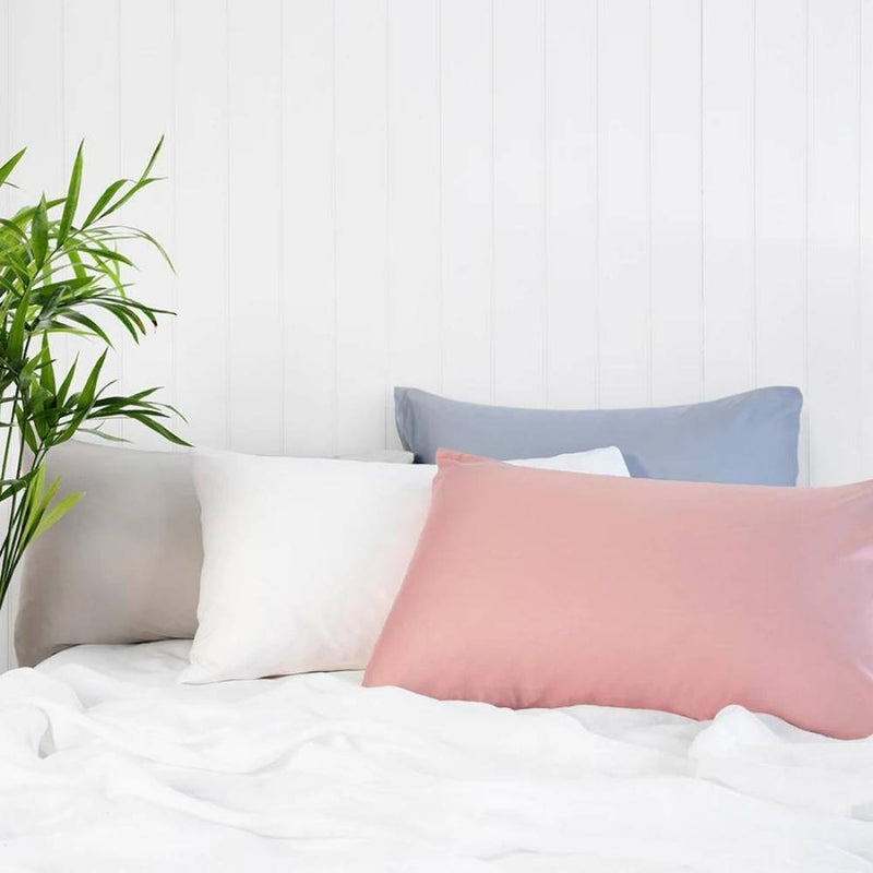 alt="Showcasing four-coloured satin pillowcases in cosy bedroom"