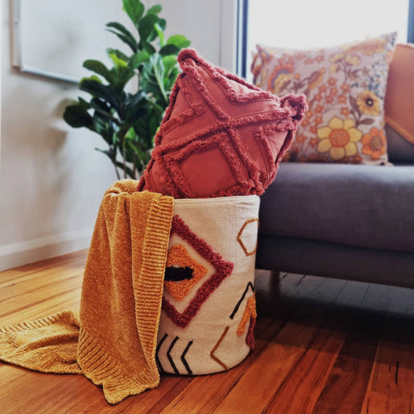 alt text="J. Elliot Ayana Red Multi Basket elegantly displays a collection of cosy cushions and throws."