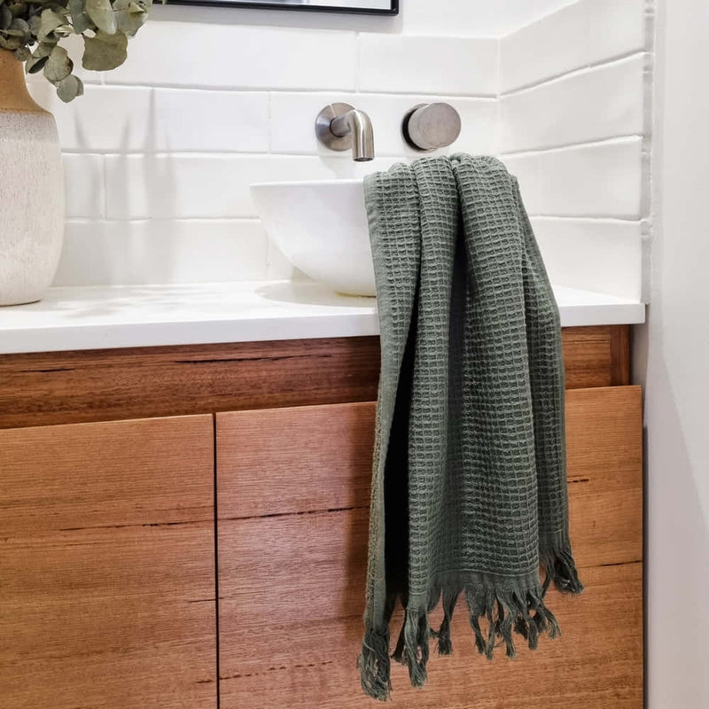 alt=" A 100% cotton, waffle weave front, terry fabric underside, and decorative fringe accents hand towels in a sink area"