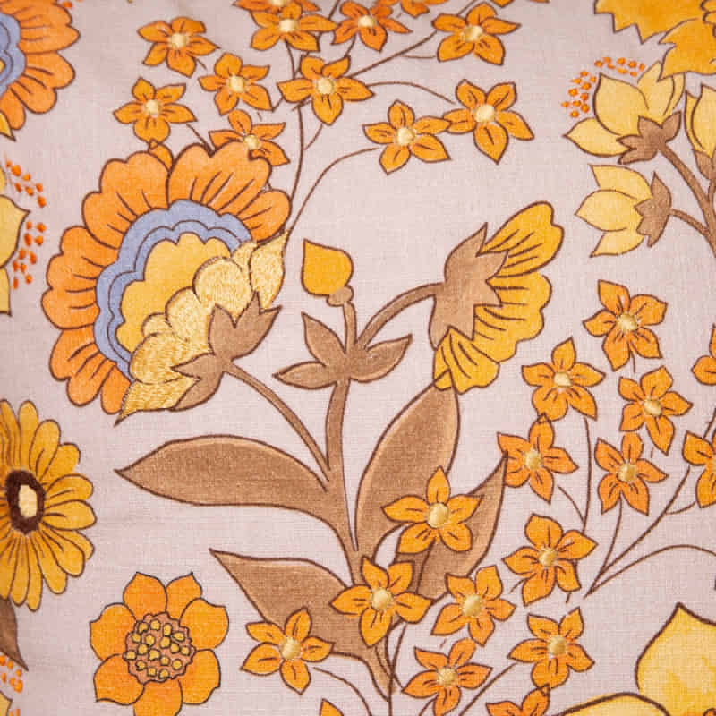alt="Close-up details of a yellow multicoloured cushion featuring beautiful and bold florals"