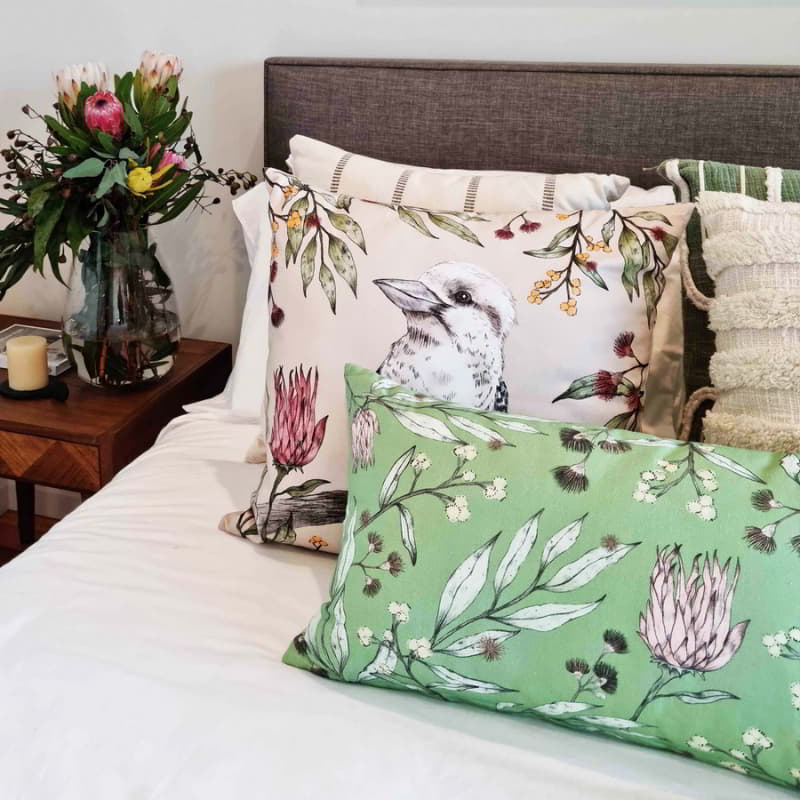 alt="A green multicoloured cushion inspired by Australian flora and fauna in a cosy bedroom."