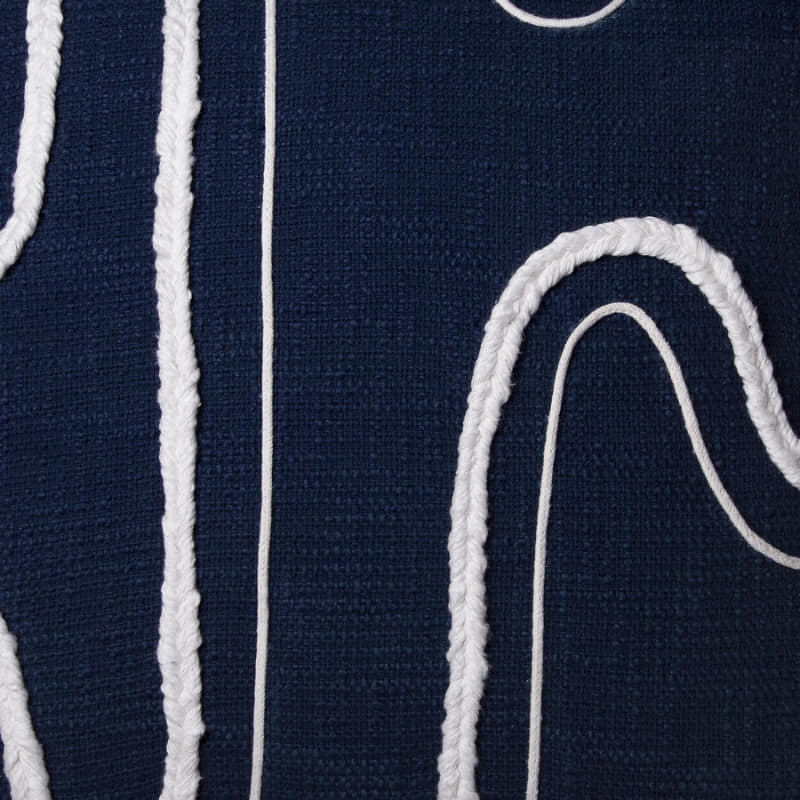 alt="Close-up details of a navy blue cushion featuring a curved white cotton braids."