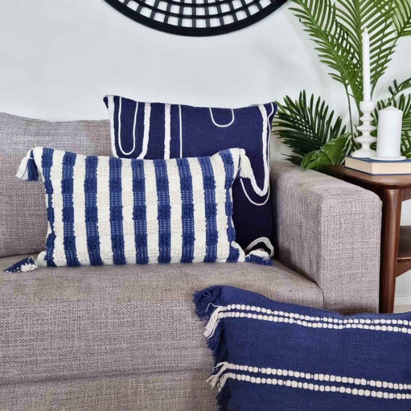 alt="A navy blue cushion featuring a curved white cotton braids in a living room."
