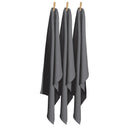  A trio of charcoal tea towels displayed on clothes pegs, emphasizing their absorbency and stylish appearance for kitchen tasks.