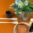 A table adorned with a pot of plants and kitchen things,  featuring a sophisticated RANS Venice Linen Terracotta Tablecloth.