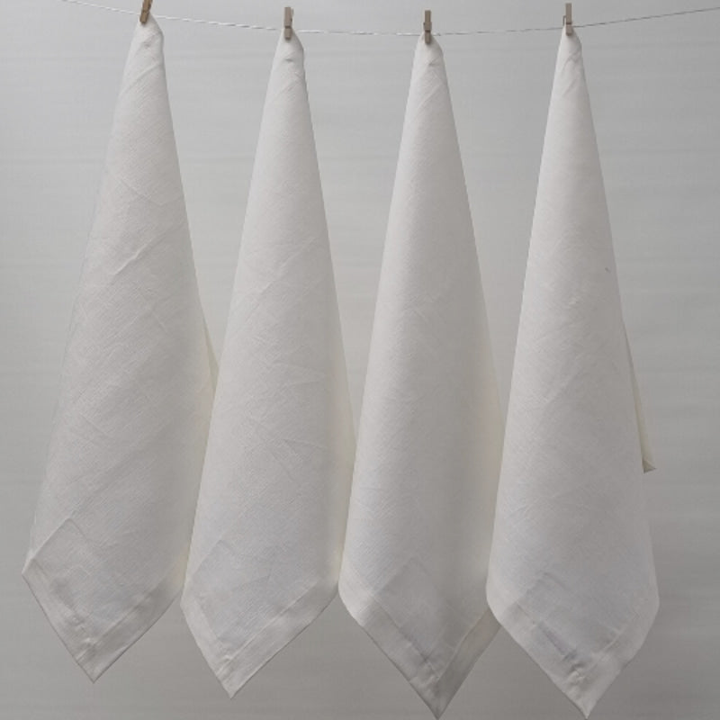 Four white napkins hanging on a clothesline, exemplifying elegance and versatility in home textiles.