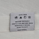 Back tag details of RANS Venice Linen White Tablecloth emphasizing practicality for effortless garment care.
